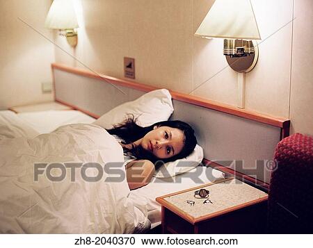 A portrait of a woman lying in a cruise ship hotel bed with her watch and earrings on the bedside table. View Large Photo Image Stock Image - A portrait of a woman lying in a cruise ship hotel bed with her watch and earrings on the bedside table.. Fotosearch