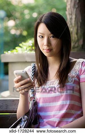 A portrait of a young woman texting on her mobile phone View Large Photo Image Picture - A portrait of a young woman texting on her mobile phone. Fotosearch