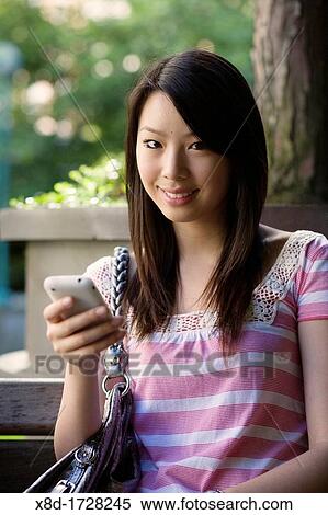 A portrait of a young woman texting on her mobile phone View Large Photo Image Stock Photography - A portrait of a young woman texting on her mobile phone. Fotosearch