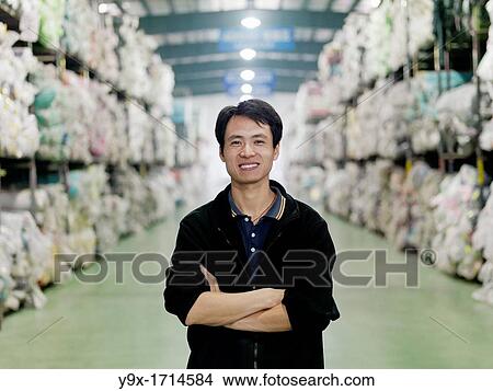 A portrait of an employee of the New Wide Kniiting and Dyeing Factory surrounded by thousands of rolls of fabric in the factory's warehouse View Large Photo Image Picture - A portrait of an employee of the New Wide Kniiting and Dyeing Factory surrounded by thousands of rolls of fabric in the factory's warehouse. Fotosearch