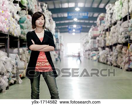 A portrait of an employee of the New Wide Kniiting and Dyeing Factory surrounded by thousands of rolls of fabric in the factory's warehouse View Large Photo Image Stock Image - A portrait of an employee of the New Wide Kniiting and Dyeing Factory surrounded by thousands of rolls of fabric in the factory's warehouse. Fotosearch
