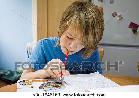 A pre-teenage boy doing his homework at the kitchen table View Large Photo Image Stock Photo - A pre-teenage boy doing his homework at the kitchen table. Fotosearch
