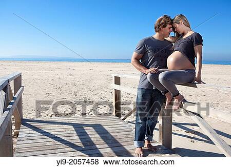 Stock Photo - A pregnant woman and her partner on the beach.. Fotosearch
