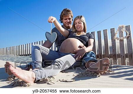 A pregnant woman and her partner sitting on the beach. View Large Photo Image Stock Photography - A pregnant woman and her partner sitting on the beach.. Fotosearch