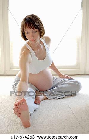 Stock Image - A pregnant woman does a stretching exercise.. Fotosearch