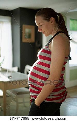 A pregnant woman in her kitchen in her 27th week of pregnancy. View Large Photo Image Stock Photo - A pregnant woman in her kitchen in her 27th week of pregnancy.. Fotosearch