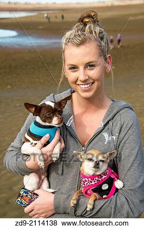 Stock Photo - A pretty girl carries to chihuahuas as she explores the dry Folsom lakebed.. Fotosearch