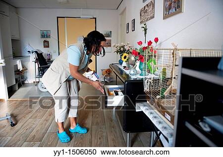 Stock Image - A professional nurse of a Rotterdam nursing home searching for medical devices in the sideboard of an inhabitant.. Fotosearch