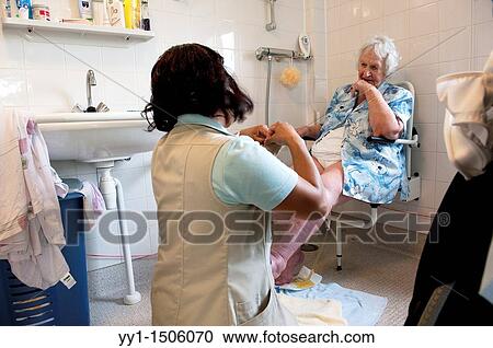 Stock Image - A professional nurse of a Rotterdam nursing home helping an elderly inhabitant getting dressed.. Fotosearch