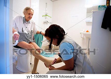 Stock Photography - A professional nurse of a Rotterdam nursing home helping an elderly inhabitant getting dressed.. Fotosearch