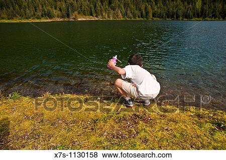 Stock Photo - A quiet and beautiful Alpin lake surrounded by snow capped mountains. Fotosearch