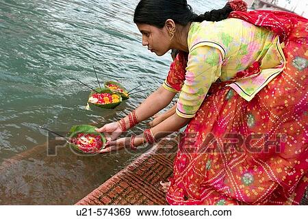 Stock Photo - A Rajasthani women doing an offering alongside the sacred river Ganges in Haridwar, a sacred place in India. Haridwar is located in Uttaranchal, at the feet of the Himalayas.. Fotosearch