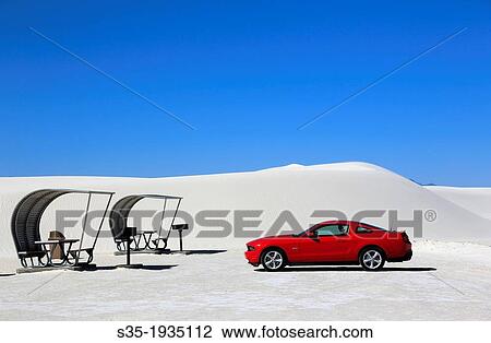 Stock Image - A red car with shaded picnic tables in the picnic area in White Sands National Monument. Alamogordo. New Mexico. USA.. Fotosearch
