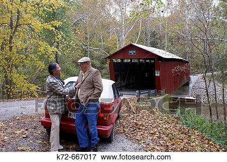 A retired couple stop to enjoy the fall day by the Rolling Stone Covered Bridge in Putnam County, Indiana, USA, which crosses the Big Walnut Creek. View Large Photo Image Stock Photo - A retired couple stop to enjoy the fall day by the Rolling Stone Covered Bridge in Putnam County, Indiana, USA, which crosses the Big Walnut Creek.. Fotosearch