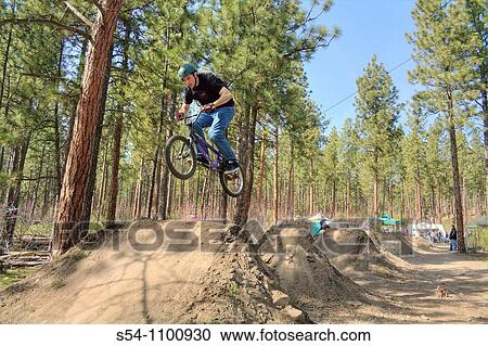 Stock Image - A rider jumps his bike at Camp Sekani Park, Beacon Hill, Spokane, Washington, USA. Fotosearch