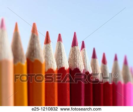 Stock Image - A row of coloured pencils photographed where the red pencil in the middle is in selective focus.. Fotosearch