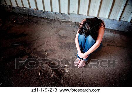 A sad woman is sitting alone on the cold concrete behind a shed View Large Photo Image Stock Image - A sad woman is sitting alone on the cold concrete behind a shed. Fotosearch