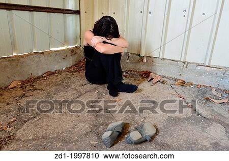 A sad woman is sitting alone on the cold concrete behind a shed. View Large Photo Image Stock Image - A sad woman is sitting alone on the cold concrete behind a shed.. Fotosearch