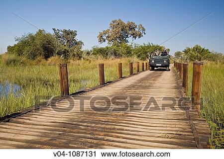 Stock Image - A safari vehicle driving over a wooden bridge in the Okavango Delta in Botswana, Africa. Fotosearch