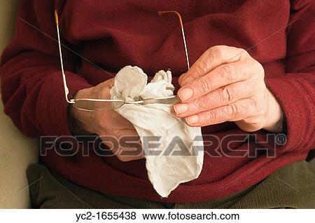 A senior elderly man in his 80's cleaning his glasses with a hankerchief at home in England, Britain, Uk View Large Photo Image Stock Photo - A senior elderly man in his 80's cleaning his glasses with a hankerchief at home in England, Britain, Uk. Fotosearch