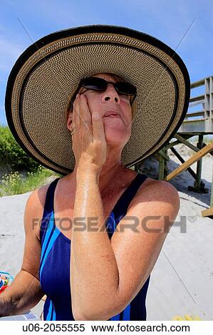 a senior woman applying sunscreen to her face at a beach View Large Photo Image Stock Photography - a senior woman applying sunscreen to her face at a beach. Fotosearch