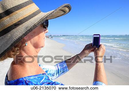 A senior woman taking pictures at a beach with a camera phone, ipod or iphone View Large Photo Image Stock Image - A senior woman taking pictures at a beach with a camera phone, ipod or iphone. Fotosearch