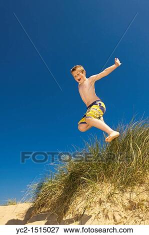 Stock Photo - A seven year old boy playing in the sand dunes at Wells-next-the-sea, Norfolk, England, Britain, Uk. Fotosearch