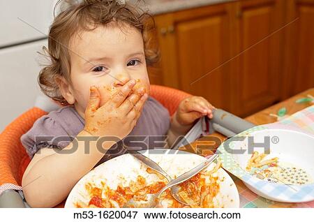 A seventeen months old baby girl eating tomato pasta using her hands View Large Photo Image Stock Photo - A seventeen months old baby girl eating tomato pasta using her hands. Fotosearch