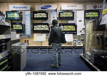 Stock Image - A shopper is dumbfounded by the selections as she browses the flat screen television display at a Best Buy electronics store in New York. Fotosearch