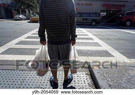 A shopper leaves a supermarket with a plastic bag holding his groceries in the New York neighborhood of Chelsea. View Large Photo Image Stock Photo - A shopper leaves a supermarket with a plastic bag holding his groceries in the New York neighborhood of Chelsea.. Fotosearch