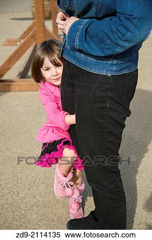 A shy young girl hides behind her mother's leg. View Large Photo Image Stock Photography - A shy young girl hides behind her mother's leg.. Fotosearch