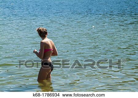 Picture - A sixteen year old girl in a bikini stands in a lake. Fotosearch