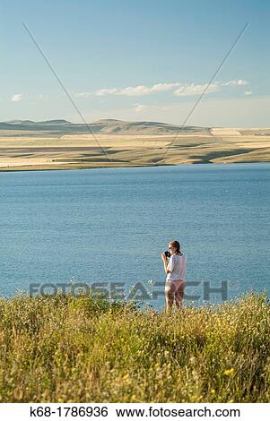 Stock Photograph - A sixteen year old girl takes photos near a lake in southern Alberta, Canada. Fotosearch