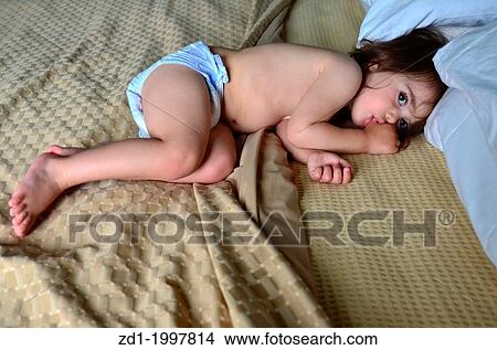A small baby is sucking her thumb in bed. View Large Photo Image Picture - A small baby is sucking her thumb in bed.. Fotosearch