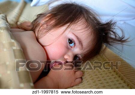 A small baby is sucking her thumb in bed. View Large Photo Image Stock Photography - A small baby is sucking her thumb in bed.. Fotosearch