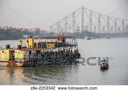 A small boat dwarfed by a ferry on the river Ganges (Hooghly) with the Howrah bridge in the background, in Kolkata (Calcutta), West Bengal, India. View Large Photo Image Stock Image - A small boat dwarfed by a ferry on the river Ganges (Hooghly) with the Howrah bridge in the background, in Kolkata (Calcutta), West Bengal, India.. Fotosearch