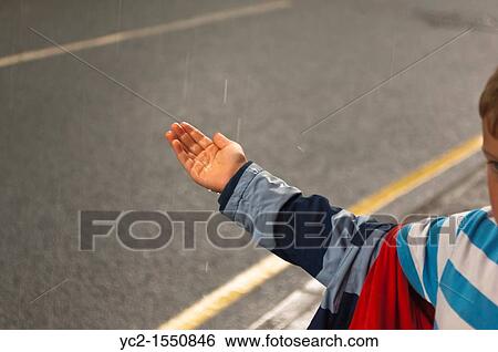 A small boy feels the rain on his hand while sheltering View Large Photo Image Stock Photograph - A small boy feels the rain on his hand while sheltering. Fotosearch