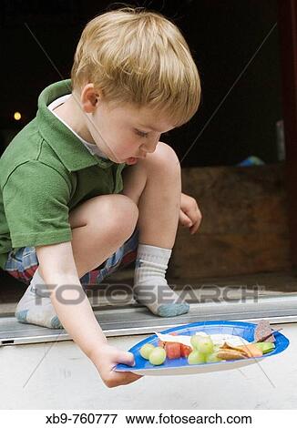 Stock Photo - A small boy with a plate of food. Fotosearch