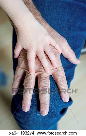 Picture - A small child's hand rests on top of his grandfather's hand. Fotosearch
