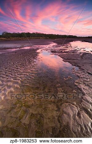 Stock Image - A small path of water in a partially dry lake bed in southern Texas under a stunning sunset sky.. Fotosearch