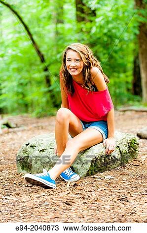 A smiling 14 year old brunette girl in shorts, sneakers and a red top in a forest setting. View Large Photo Image Stock Image - A smiling 14 year old brunette girl in shorts, sneakers and a red top in a forest setting.. Fotosearch