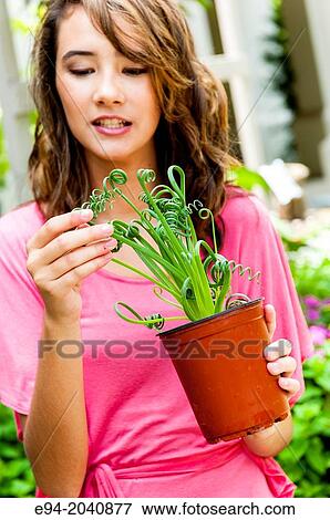 A smiling 14 year old brunette looking at a plant in plant nursery. View Large Photo Image Stock Photo - A smiling 14 year old brunette looking at a plant in plant nursery.. Fotosearch