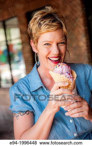 A smiling 44 year old blond woman holding an ice cream cone looking at the camera. View Large Photo Image Stock Photo - A smiling 44 year old blond woman holding an ice cream cone looking at the camera.. Fotosearch