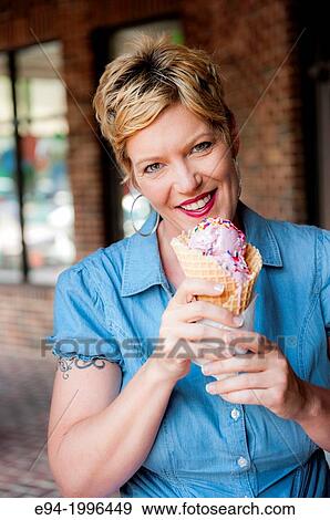 Stock Photo - A smiling 44 year old blond woman holding an ice cream cone looking at the camera.. Fotosearch