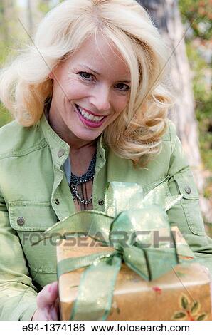A smiling 44 year old blond woman holding a wrapped present View Large Photo Image Stock Photograph - A smiling 44 year old blond woman holding a wrapped present. Fotosearch