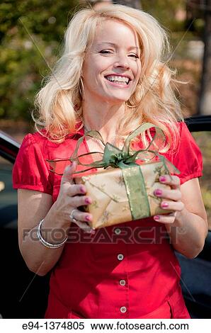 Stock Photography - A smiling 44 year old blond woman holding a wrapped present. Fotosearch