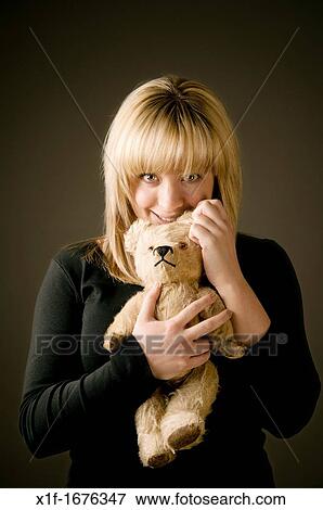 a smiling blonde haired teenage girl woman cuddling holding her old battered teddy bear View Large Photo Image Stock Photo - a smiling blonde haired teenage girl woman cuddling holding her old battered teddy bear. Fotosearch