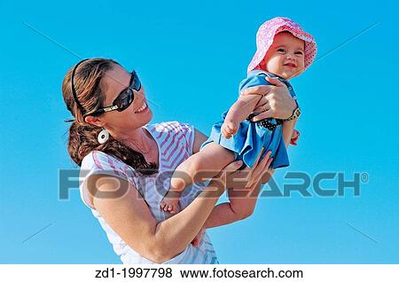 A smiling child and her mother play together on a sunny day. View Large Photo Image Stock Photo - A smiling child and her mother play together on a sunny day.. Fotosearch
