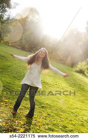 Stock Photography - A smiling teen girl playing in the rain outdoors.. Fotosearch