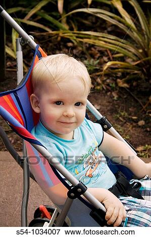 Stock Photo - A smiling toddler sits in a stroller.. Fotosearch